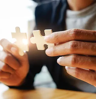 Two hands joining puzzle pieces, representing partnership